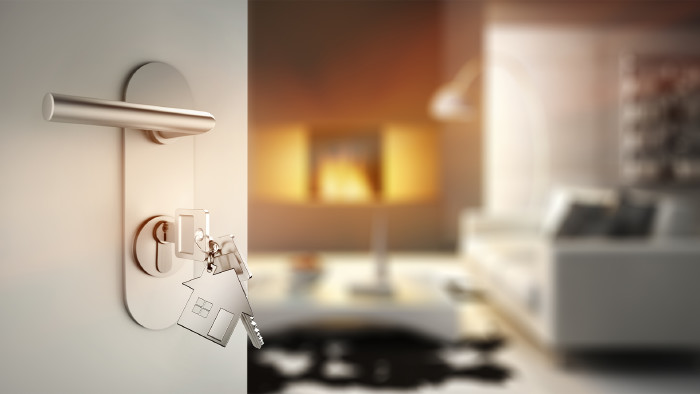 © peterschreiber.media, stock.adobe.com Offene Tür mit Schlüsseln vor gemütlichem Raum mit Sofa und Kamin