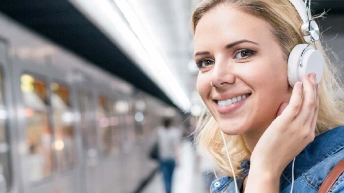 © Halfpoint, Fotolia Pendlerin mit Headphones am Bahnhof